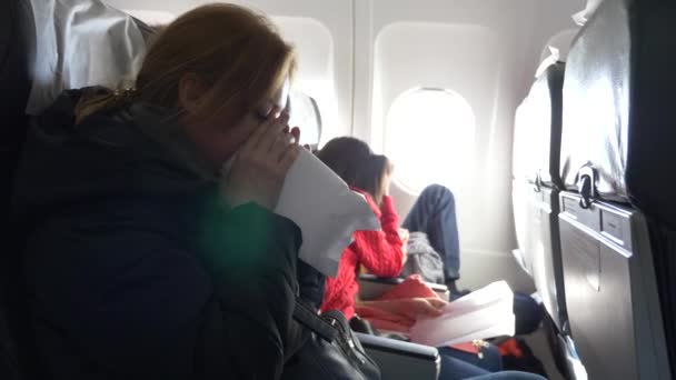 Femme dans un avion avec des enfants sur un fond hublot. 4k l'avion est entré dans la zone de turbulence. la fille a commencé à paniquer, elle respire dans un sac en papier . — Video