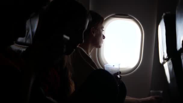Женщина в самолете с детьми на фоне иллюминатора. 4k — стоковое видео
