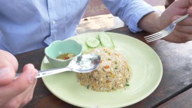 yakın çekim. 4 k. adam sıkar limon suyu üzerinde heyecan ile bir tabak kızarmış pirinç yasemin yumurta karides, dekore edilmiş ve salatalık ile.