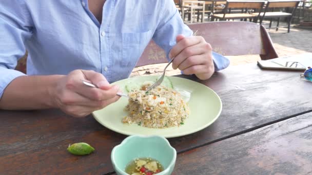 Close-up. 4 k. man knijpt limoensap op een schotel met roer gebakken jasmijn rijst met ei en garnalen, versierd met komkommer. — Stockvideo