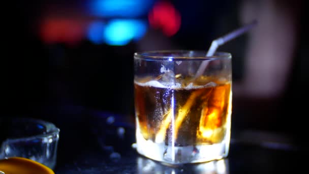 Крупный план алкогольного коктейля в стакане на барной стойке, в ночном клубе. размытие фона, 4k — стоковое видео