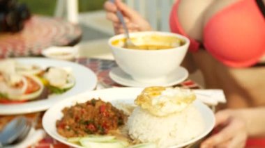 Baharatlı karides çorbası ekşi ve baharatlı tadı ile Tay bir yemektir. Busty Kız bikinili Tom Yam havuzun yanında bir masada yemek yer. 4 k, yavaş hareket, yakın çekim. seyahat turizm kavramı