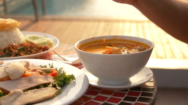 La soupe de crevettes est un plat thaïlandais au goût aigre et épicé. l'homme mange Tom Yam à une table près de la piscine. 4k, ralenti, gros plan. concept de tourisme touristique — Video