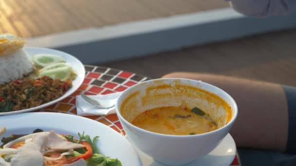 La sopa de camarones es un plato tailandés con un sabor agrio y picante. El hombre se está comiendo a Tom Yam en una mesa junto a la piscina. 4k, cámara lenta, primer plano. concepto de turismo turístico — Vídeos de Stock