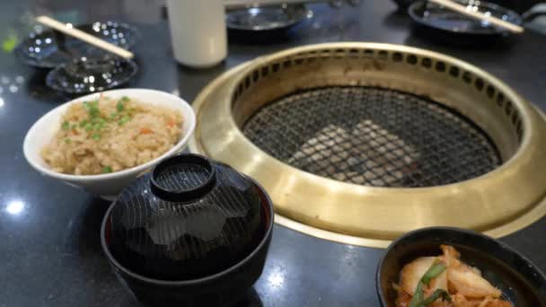 Barbecue coreano. la gente cucina e mangia piatti cucinati su una griglia coreana in un ristorante. 4k, primo piano . — Video Stock