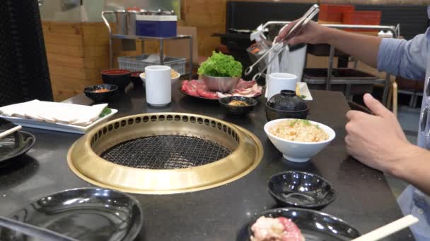 Barbecue coréen. les gens cuisinent et mangent des plats cuisinés sur un gril coréen dans un restaurant. 4k, gros plan . — Video