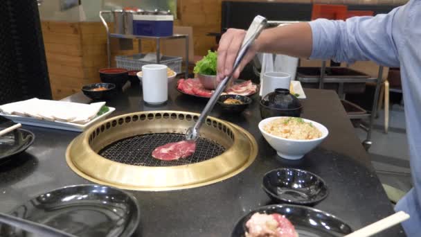 Barbecue coréen. les gens cuisinent et mangent des plats cuisinés sur un gril coréen dans un restaurant. 4k, gros plan . — Video