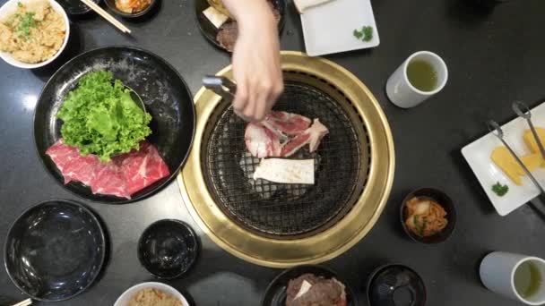 Barbecue coréen. les gens cuisinent et mangent des plats cuisinés sur un gril coréen dans un restaurant. 4k, gros plan . — Video