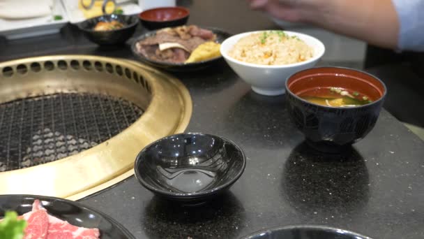 Churrasqueira coreana. as pessoas cozinham e comem pratos cozidos em um churrasco coreano em um restaurante. 4k, close-up . — Vídeo de Stock