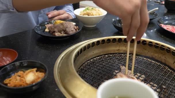 Корейська барбекю гриль. люди готувати і їсти страви, приготовані на Корейському гриль у ресторані. 4 Кбайт, великим планом. — стокове відео