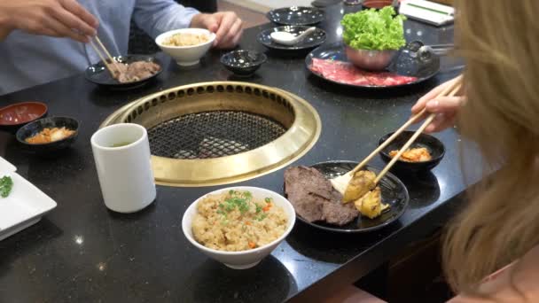 韩国烤肉架。人们在一家餐馆的韩国烤肉架上烹调和吃菜肴。4k、特写. — 图库视频影像