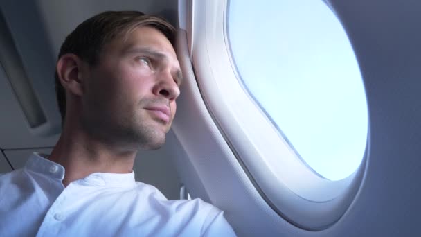 4k, primer plano. retrato de un joven guapo que mira a la ventana del avión durante el vuelo . — Vídeos de Stock