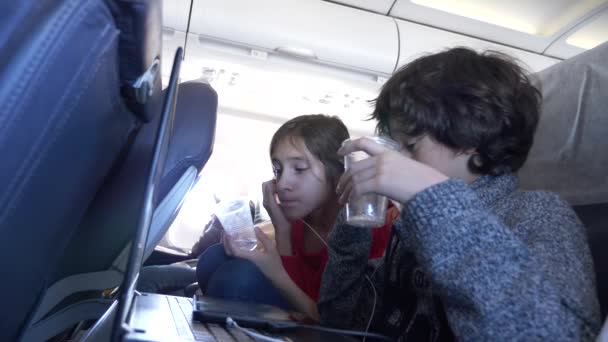 4k, primer plano, niños, pasajeros beben agua de vasos desechables en el avión durante el vuelo contra el ojo de buey . — Vídeos de Stock