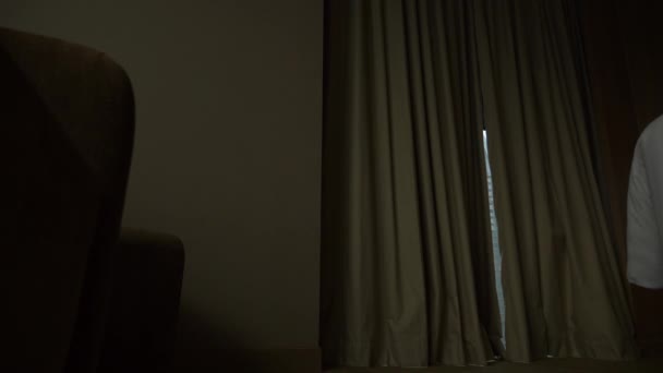 Чоловік у шортах відкриває штори на вікно, вид з вікна на хмарочоси. 4k Повільний рух — стокове відео