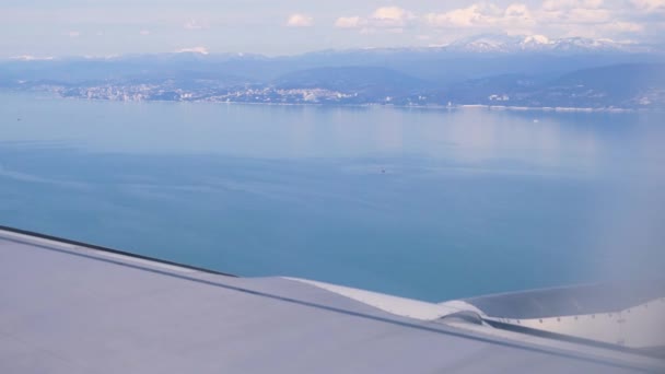 Ala di ala di aereo. Vista del mare e delle montagne dall'aereo durante il decollo o l'atterraggio. 4k — Video Stock