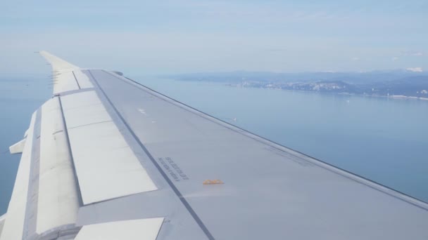 Vleugel van de vleugel van een vliegtuig. Een zicht op de zee en de bergen uit het vliegtuig tijdens opstijgen of de landing. 4k — Stockvideo