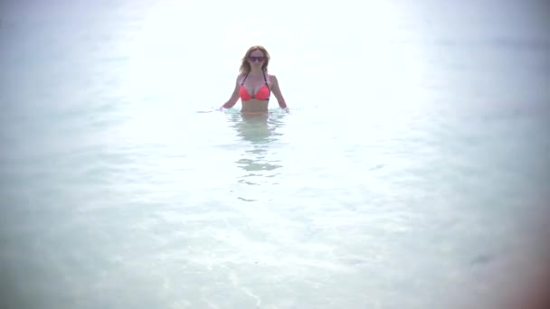 Schönes junges Mädchen, das in Zeitlupe aus dem Meer kommt und einen roten Bikini trägt. Tropenurlaub. 4k — Stockvideo