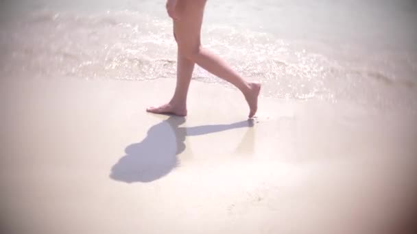 Zeitlupe weiblicher Beine, die ins Wasser plätschern. Mädchen laufen barfuß über den Sandstrand. 4k — Stockvideo