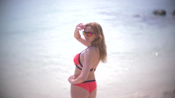 Οπίσθια όψη όμορφη νεαρή κοπέλα στην παραλία πίσω σε αργή κίνηση, φοράει κόκκινο μπικίνι σέξι πισινό τροπικές διακοπές. κοντινό πλάνο. 4k — Αρχείο Βίντεο