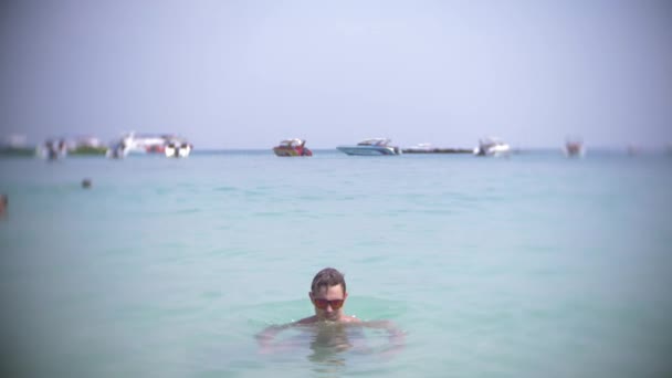 4k, Slowmotion-skytte, en ung man dyk i havet bär solglasögon. framträder och ler — Stockvideo