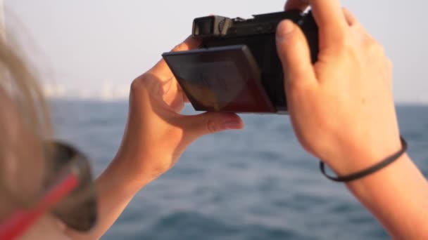 Egy gyönyörű nő áll a stern, a hajó, és tesz egy videót a kamera. Hullámok a háttérben, lassú mozgás, 4k — Stock videók