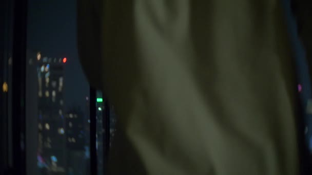 Ένα νεαρό ζευγάρι είναι φιλώντας στο φόντο της ένα πανοραμικό παράθυρο με θέα στην πόλη. Το βράδυ της νύχτας. 4k, θάμπωμα του φόντου — Αρχείο Βίντεο