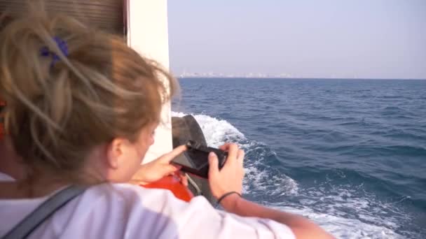 Güzel bir kadının geminin kıç tarafında duruyor ve bir video kamera üzerinde yapar. Dalgalar içinde geçmiş, ağır çekim, 4k — Stok video
