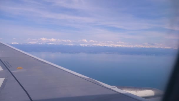 Ala di ala di aereo. Vista del mare e delle montagne dall'aereo durante il decollo o l'atterraggio. 4k — Video Stock