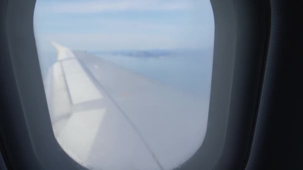 机翼翼的飞机。从飞机起飞或着陆时的海面和山脉的景色。4k — 图库视频影像