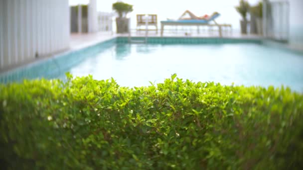 Eine Frau im rosafarbenen Bikini genießt den Blick auf das Meer am Pool auf dem Dach, das Mädchen sonnt sich auf einer Liege. 4k, Zeitlupe — Stockvideo