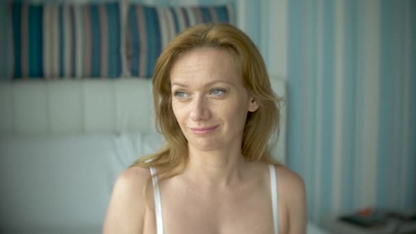Wanita muda yang menarik dengan celana dalam putih tersenyum dalam kamera close-up, 4k, gerak lambat — Stok Video