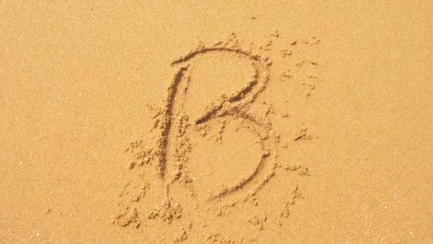 The sea wave erases the inscriptions written on the sand. 4k, slow-motion, top view, the letter b — Stock Video