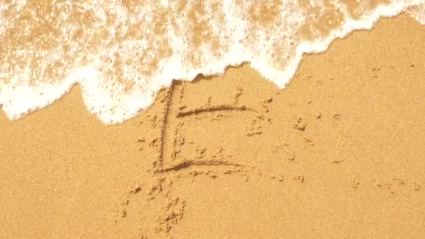 Mořská vlna maže nápisy napsané na písku. 4k, pomalý pohyb, pohled shora. písmeno e — Stock video