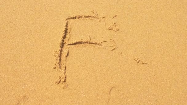 The sea wave erases the inscriptions written on the sand. 4k, slow-motion, top view. the letter f — Stock Video