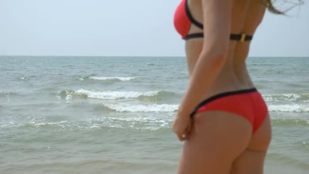 Rear view beautiful young girl at the beach back in slow motion wearing red bikini sexy butt tropical vacation. Закрывай. 4k — стоковое видео