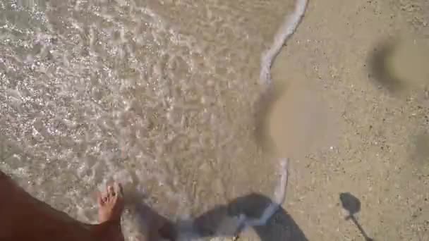 Movimiento lento de las piernas masculinas corriendo salpicando en el agua. tipo correr descalzo en la playa de arena. 4k — Vídeos de Stock