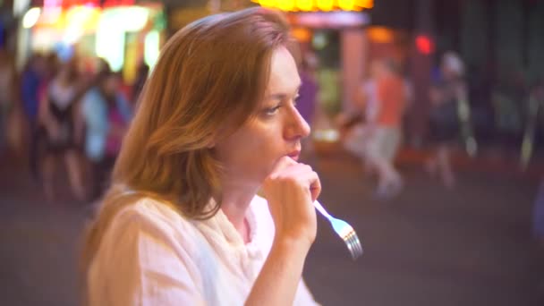 Giovane e bella donna mangiare dessert, seduto fuori in un caffè o terrazza. Una donna ammira un taglio di frutta. 4k . — Video Stock