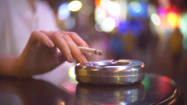 Närbild, skakar hand med en cigarett aska i en askkopp. en enda kvinna sitter på ett café utanför lokalen, röka en cigarett, mot bakgrund av en fullsatt gatan 4k, oskärpa den — Stockvideo