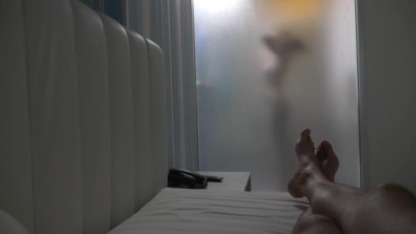 Woman behind blurry glass. Girl preparing take shower. Woman in bathroom. a man watches as a woman takes a shower through a glass wall in the shower. 4k — Stockvideo