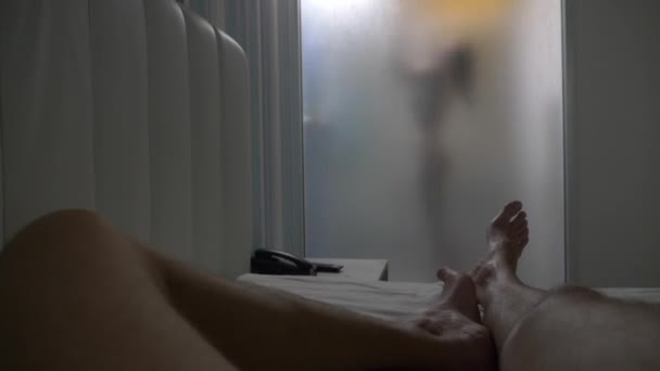 Femeia din spatele sticlei neclare. Fata se pregăteşte să facă duş. Femeie în baie. Un bărbat se uită cum o femeie face un duș printr-un perete de sticlă în duș. 4k — Videoclip de stoc