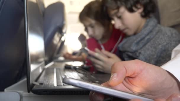 4k, крупним планом, діти, пасажири використовують телефон у літаку проти отвору . — стокове відео
