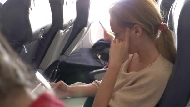 4k, Nahaufnahme, weibliche Nutzung des Telefons im Flugzeug gegen ein Bullauge. — Stockvideo