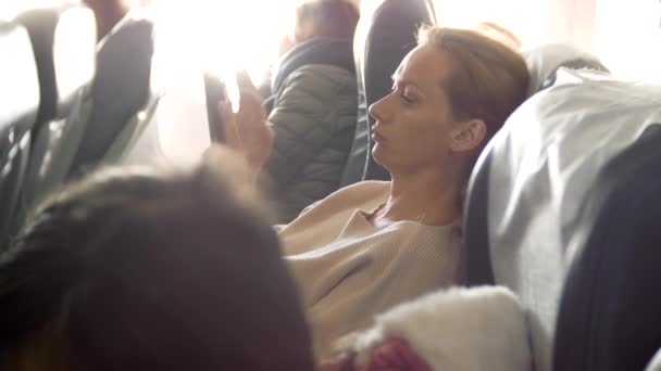 4k, gros plan, femme utiliser le téléphone dans un avion contre un hublot . — Video