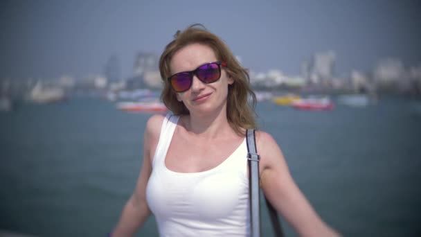 Bir kadın güneş gözlüğü iskelede duran tekneler izliyor. 4k, arka plan, yavaş hareket bulanıklığı — Stok video