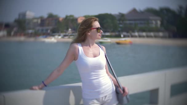 Een vrouw in zonnebril kijken naar de boten die permanent op de pier. 4k, blur achtergrond, slow-motion — Stockvideo