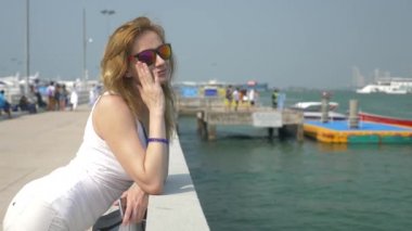 bir kadın güneş gözlüğü iskelede duran tekneler izliyor. 4k, arka plan bulanıklık