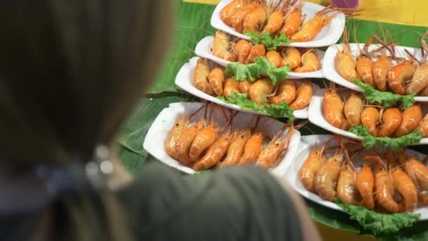 Uma mulher olha para os produtos no mercado noturno. Comida de rua tailandesa. mercado noturno na Tailândia, 4k — Vídeo de Stock