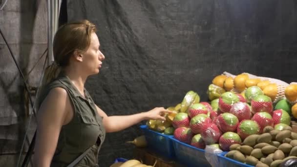 Marché asiatique, fruits exotiques. une femme choisit des fruits dans un marché de nuit en Thaïlande. 4k — Video