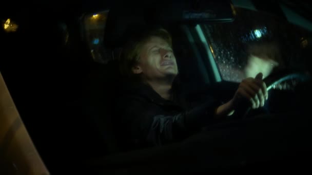 Kobieta w kurtce siedzi w samochodzie płacz. noc i deszcz, 4k, tło rozmycie — Wideo stockowe