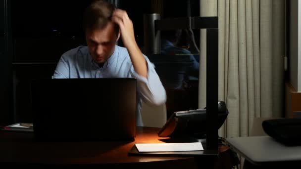 Junger Geschäftsmann, der am Festnetztelefon telefoniert und nachts am Schreibtisch im Büro sitzt. Notizbuch vorne. 4k — Stockvideo